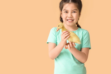 Little girl with cute duckling on color backgroundの写真素材