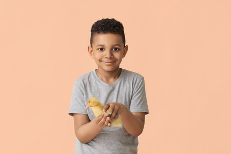 Little African-American boy with cute duckling on color backgroundの写真素材