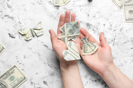 Woman making origami figures from dollar banknotes at tableの写真素材