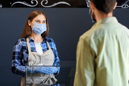 Female barista with client in modern cafe. concept of epidemic