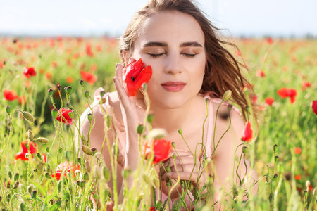 beautiful young woman in poppy fieldの写真素材