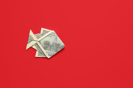 Origami fish made of dollar banknote on color backgroundの写真素材