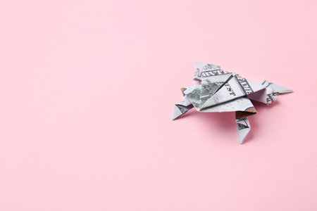 Origami frog made of dollar banknote on color backgroundの写真素材
