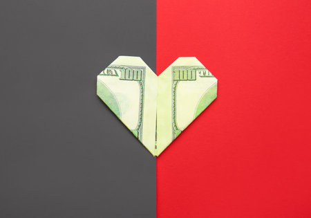 Origami heart made of dollar banknote on color backgroundの写真素材