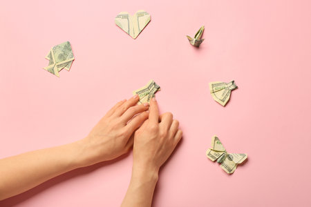 Woman making origami figures from dollar banknotes on color backgroundの写真素材