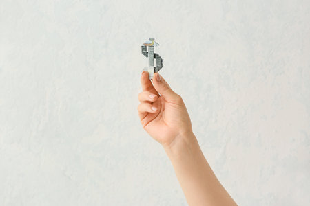 Female hand with origami figure made of dollar banknotes on light backgroundの写真素材