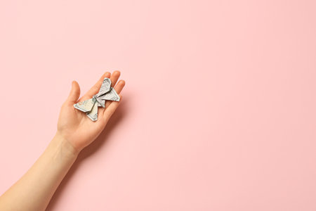 Female hand with origami butterfly made of dollar banknote on color backgroundの写真素材