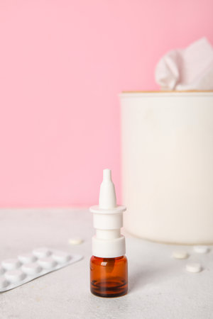 Nasal drops with pills and tissue box on table near pink wall. Allergy conceptの写真素材