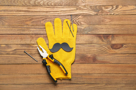 Paper mustache with glove, pliers and nails on wooden background. father's day celebrationの写真素材