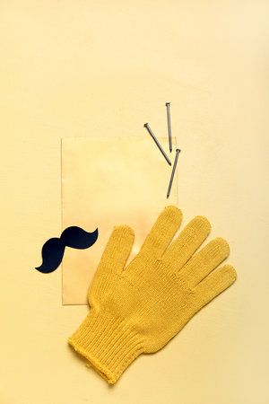 Blank card with paper mustache, glove and nails on yellow background. father's day celebrationの写真素材