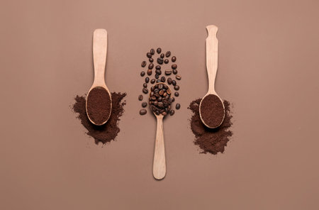Spoons of coffee powder and beans on brown background