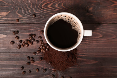 Cup of coffee with powder and beans on dark wooden backgroundの写真素材