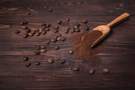 Scoop of coffee powder and beans on dark wooden backgroundの写真素材