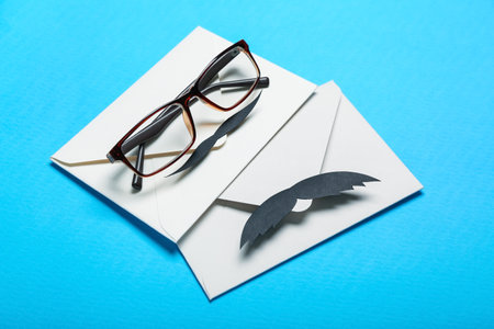 Envelopes with paper mustache and eyeglasses on color background. father's day celebrationの写真素材
