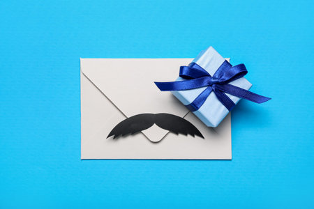 Envelope with paper mustache and gift for Father's Day celebration on color background