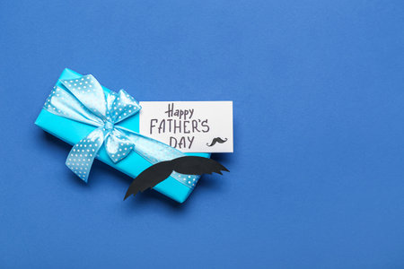 Gift box, paper mustache and card with text HAPPY FATHER'S DAY on color backgroundの写真素材