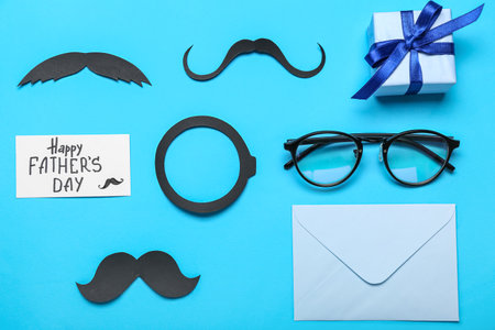 Composition with paper decor, eyeglasses and gift for Father's Day celebration on color backgroundの写真素材