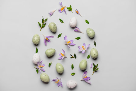 Composition with Easter eggs, plant leaves and crocus flowers on light background