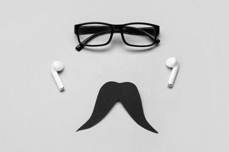 Black paper mustache, eyeglasses and earphones on gray backgroundの写真素材