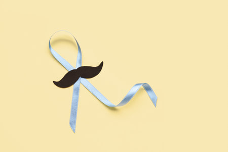Light blue awareness ribbon with black paper mustache on color backgroundの写真素材