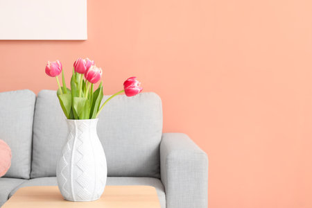 Vase with tulips on table near sofa in living roomの写真素材