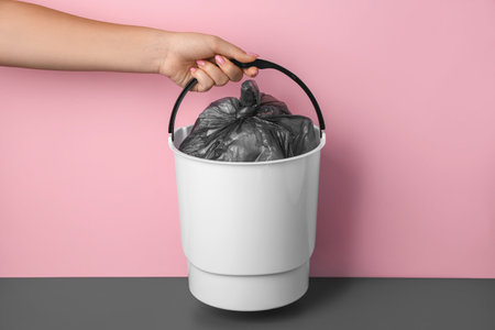 Woman with rubbish bin near pink wallの写真素材