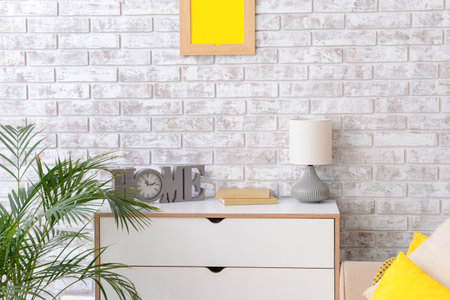 Modern chest of drawers with lamp near brick wall in roomの写真素材