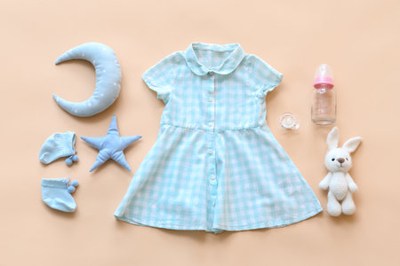 Baby clothes with bottle, pacifier and toys on color backgroundの写真素材