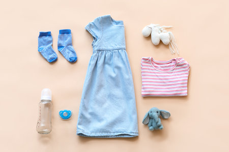 Baby clothes with bottle, pacifier and toys on color backgroundの写真素材