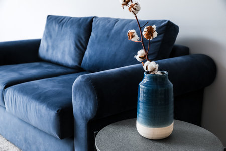 Stylish sofa and table with cotton flowers near light wall in roomの写真素材