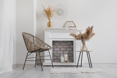 Stylish fireplace with armchair and table in interior of living roomの写真素材