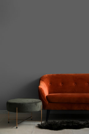 Stylish sofa with pouf near gray wall in roomの写真素材