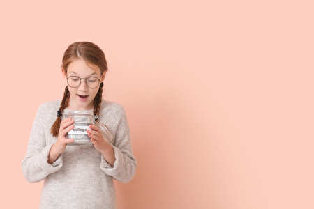 Surprised girl with savings for education on color background