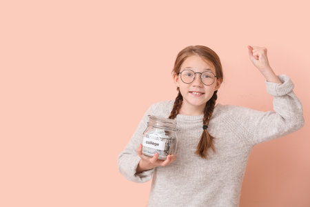 Happy girl with savings for education on color backgroundの写真素材