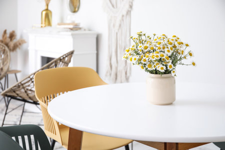 Vase with beautiful chamomiles on table in roomの写真素材