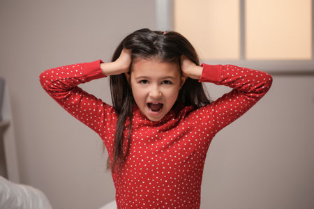 Screaming little girl suffering from sleep disorder in bedroom