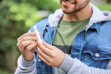 Handsome young man with lip balm outdoorsの写真素材