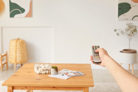 Young man with TV remote control at homeの写真素材
