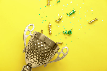 Gold cup with stars and serpentine on yellow background, closeup