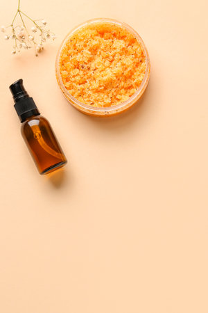 Jar of body scrub, essential oil and gypsophila flowers on color backgroundの写真素材