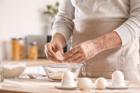 Male chef making dough for pasta at table in kitchen, closeupの写真素材