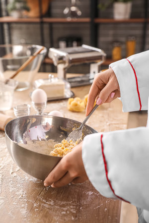 Female chef making dough for pasta at table in kitchen, closeupの写真素材