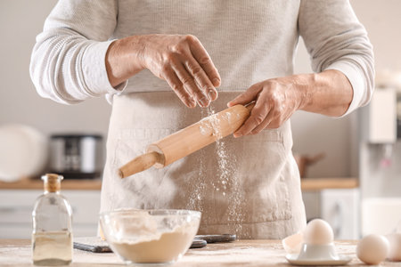 Male chef making dough for pasta at table in kitchen, closeup
