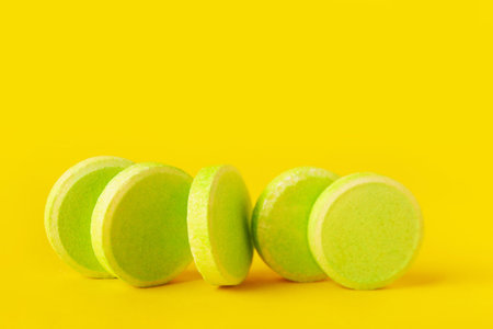 Green soluble tablets on yellow background