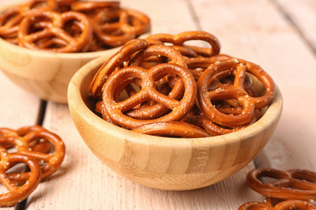 Bowls of tasty pretzels on light wooden background, closeupの写真素材
