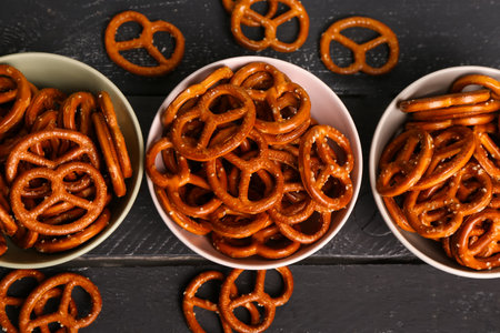Bowls with tasty pretzels on dark color background, closeupの写真素材