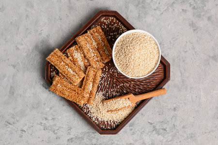 Board with tasty kozinaki and sesame seeds on grunge backgroundの写真素材