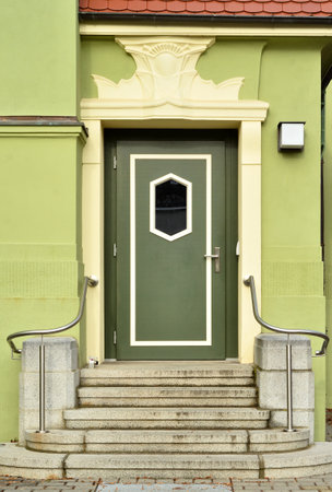 View of green building with wooden door and stepsの写真素材