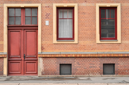 View of brick building with red door and windowsの写真素材