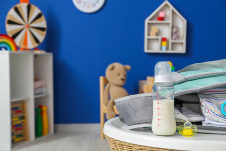 Bottle of milk for baby with accessories on table in roomの写真素材